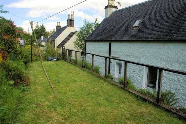 The rear garden at Bruaich Cottage, Lochcarron, slopes upwards steeply but there is a level, grassy area at the foot of the slope.